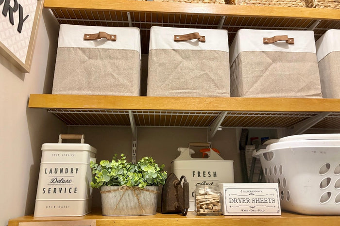 Shelving unit with storage bins, laundry basket, and decorative items in a laundry room.